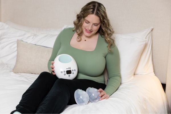 Breastfeeding mom holding the Motif Luna with Breast Milk Collection Cups