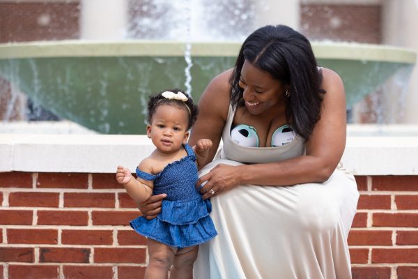 mom outside playing with her baby while pumping with the Motif Aura Glow