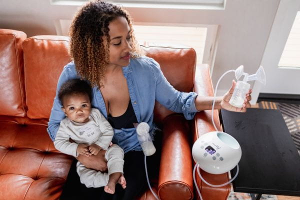 mom holding baby while pumping with the Motif Luna Double Electric breast pump
