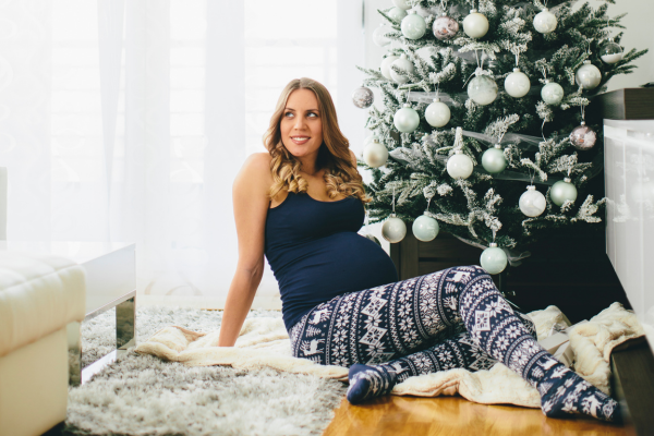 pregnant #motifmom taking a maternity holiday photo in front of a christmas tree