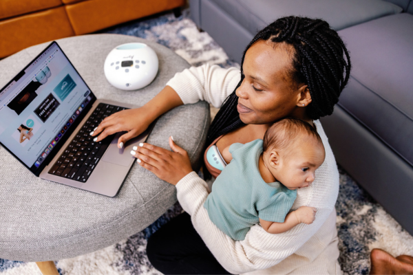 Mother working while breastfeeding with her Motif Luna. She is holding her child in her arms. 