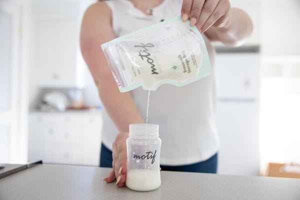 mom pour milk from a motif milk storage bag into a motif milk collection container