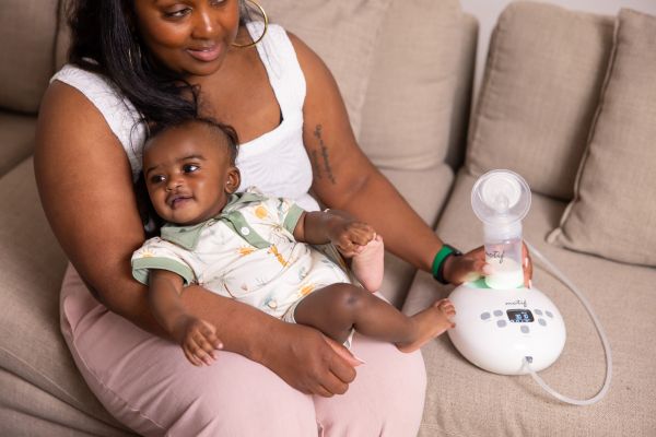Mom holding her baby using the Motif Luna Double Electric Breast Pump